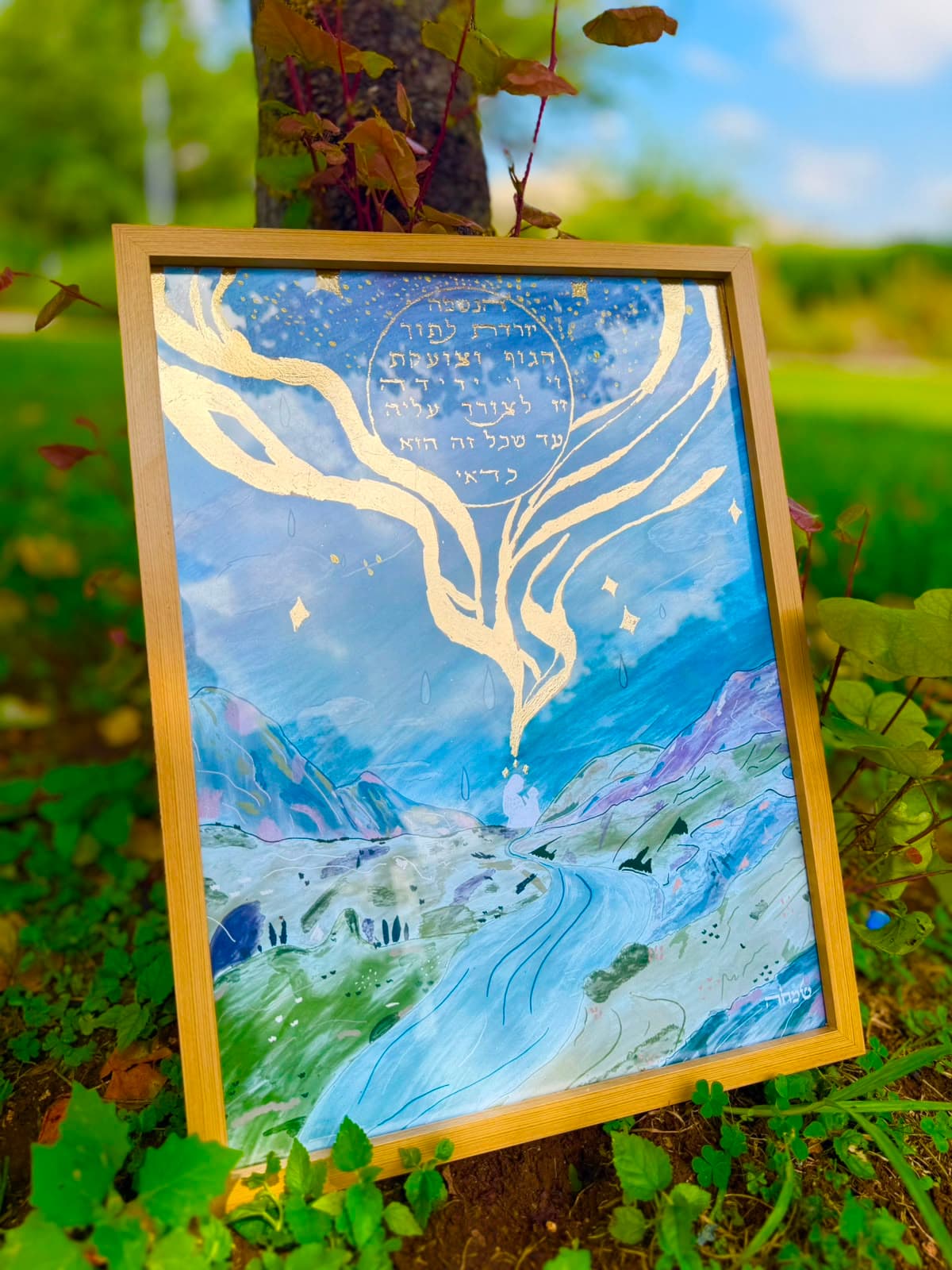 The Soul Descends — framed gold-leaf artwork resting against a tree