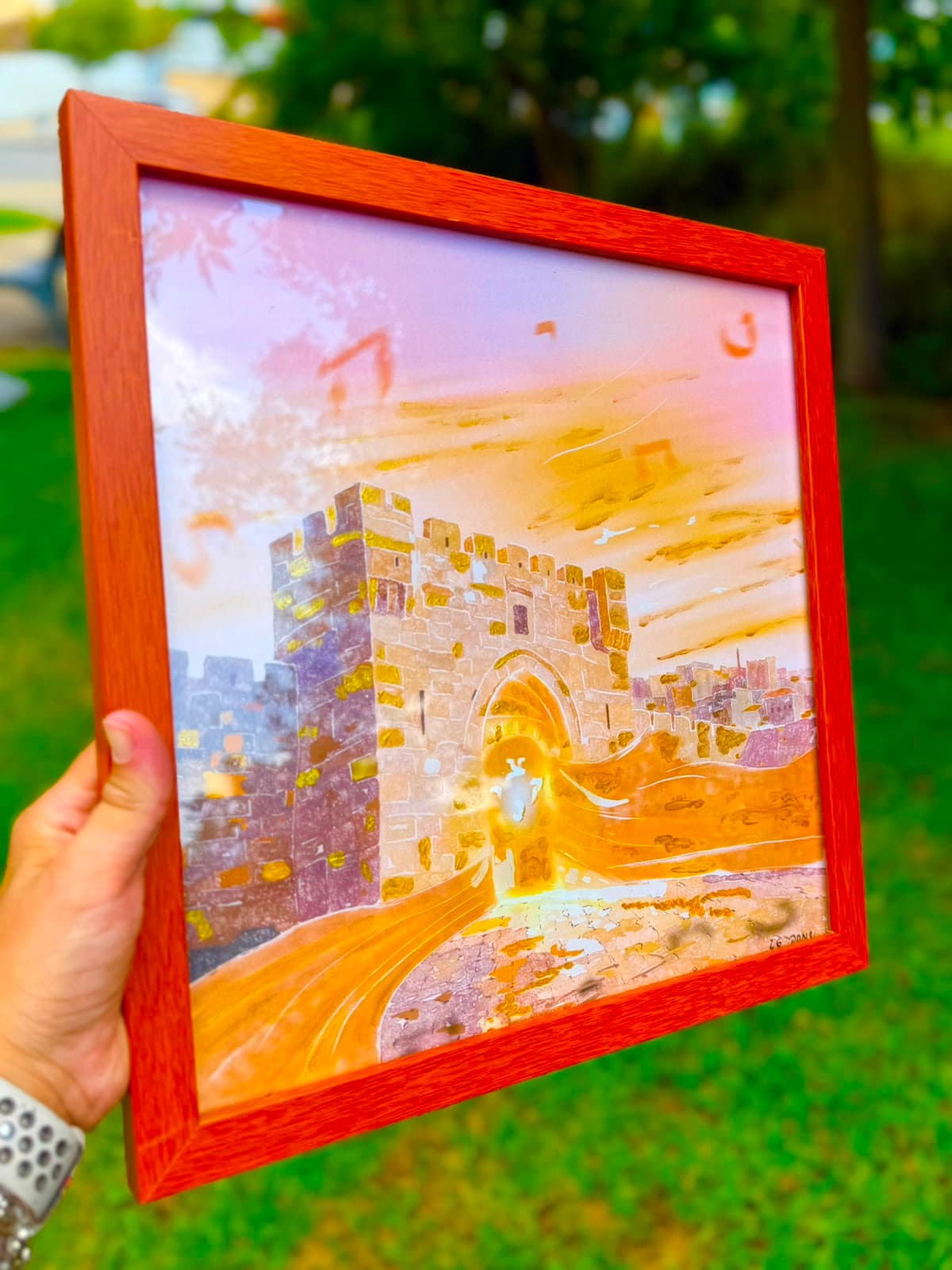 Ufaratza framed artwork held up outdoors, gold gates glowing