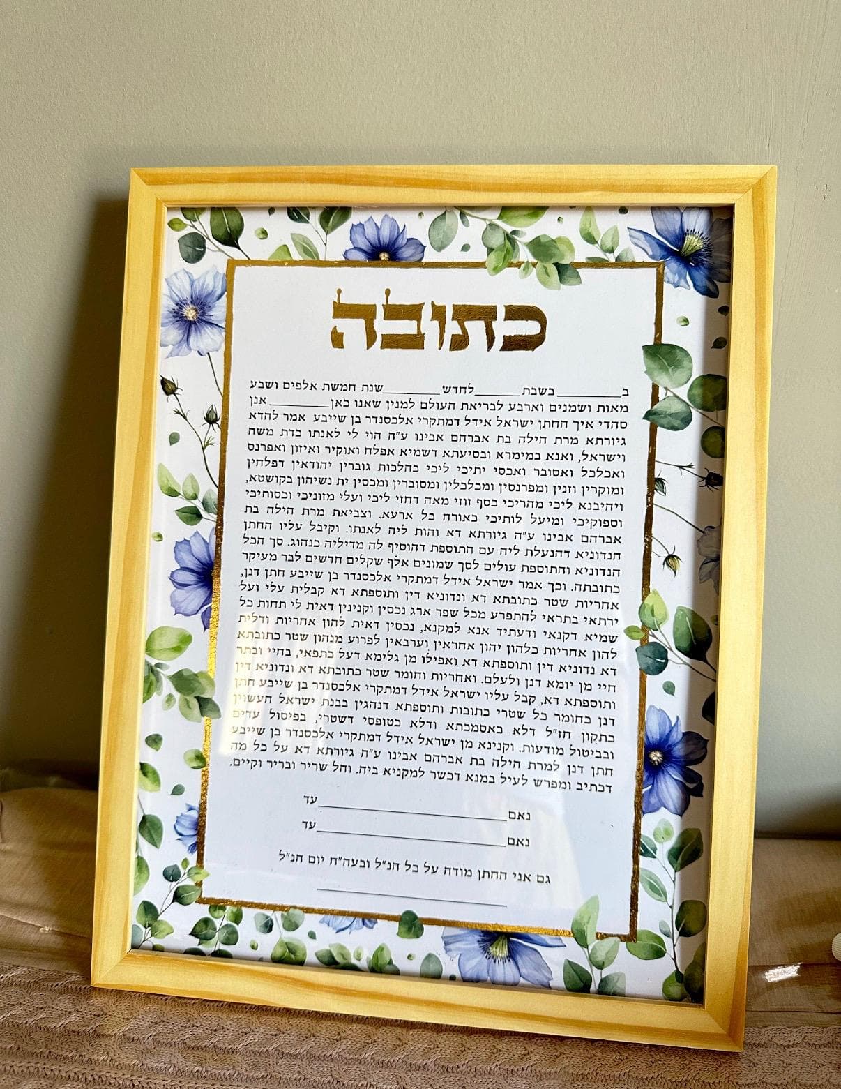 Blue floral ketubah with eucalyptus leaves in gold frame