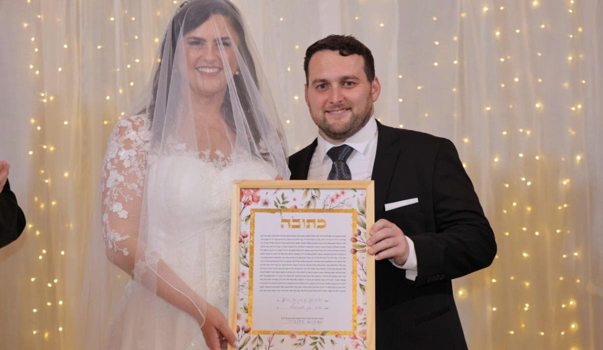 Couple holding their floral ketubah at wedding ceremony